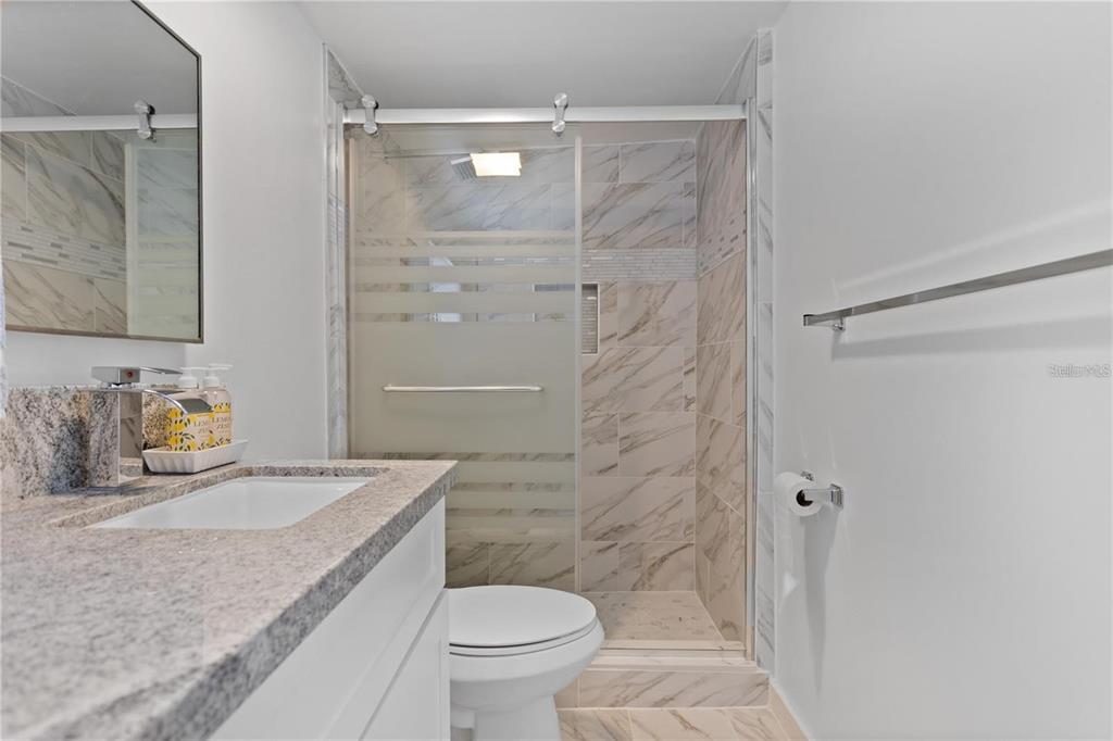 904 Lakeview Road, Unit A Clearwater, FL 33756 - Photo 12 of 25 a bathroom with a granite countertop sink toilet and shower