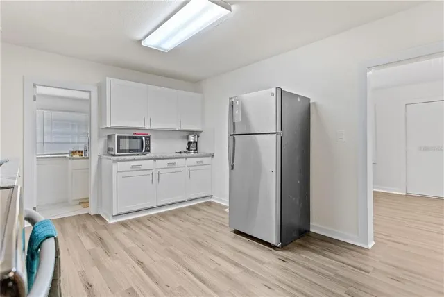 a kitchen with a refrigerator a white cabinets and wooden floor