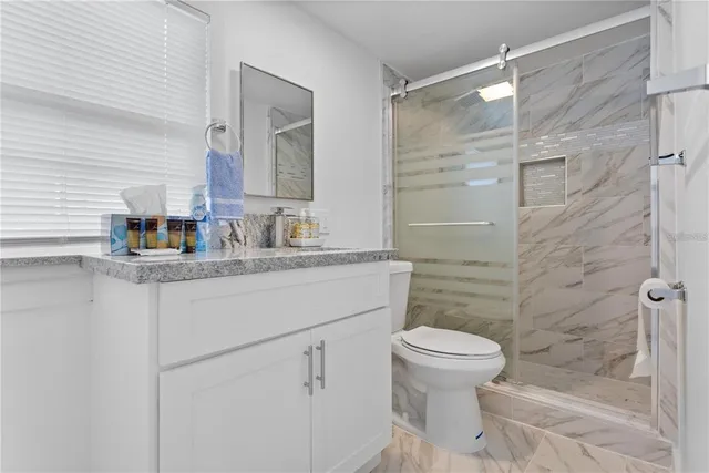 a bathroom with a granite countertop sink toilet and shower