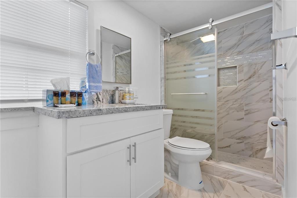 904 Lakeview Road, Unit A Clearwater, FL 33756 - Photo 9 of 25 a bathroom with a granite countertop sink toilet and shower