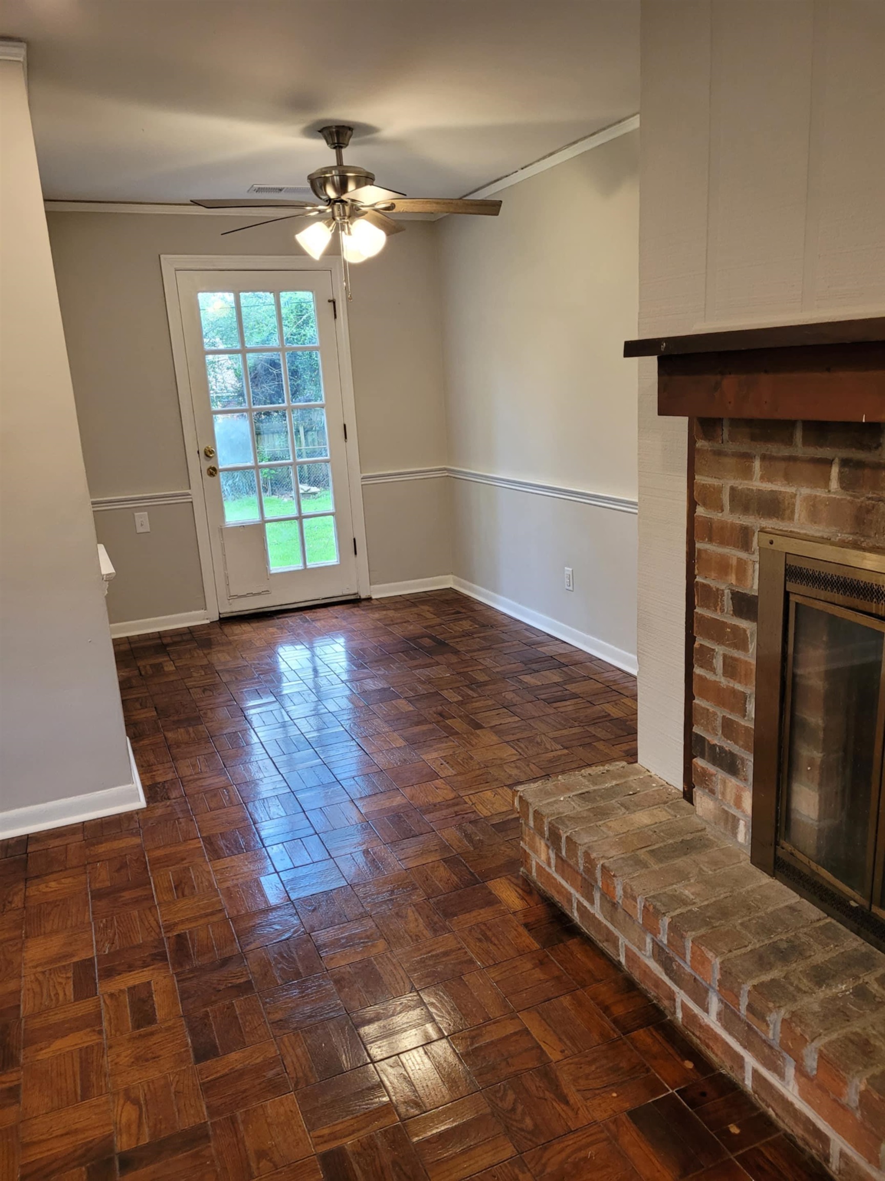 5055 Wingdale Road Memphis, TN 38117 - Photo 12 of 20 Unfurnished living room featuring parquet flooring, a brick fireplace, ceiling fan, and crown molding
