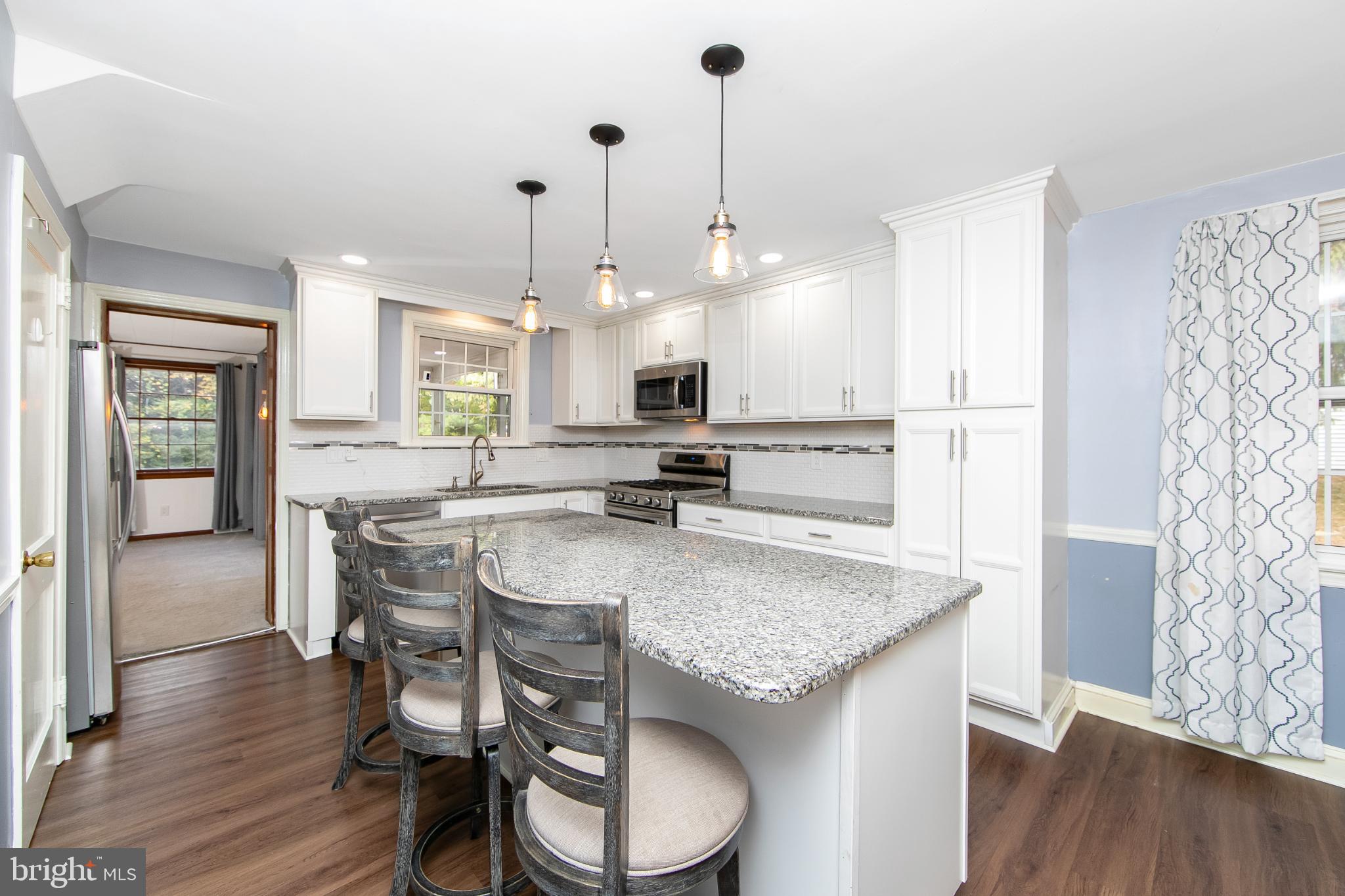 414 Stanfield Road Springfield, PA 19064 - Photo 3 of 51 a kitchen with stainless steel appliances granite countertop a stove a sink dishwasher a dining table and chairs with wooden floor