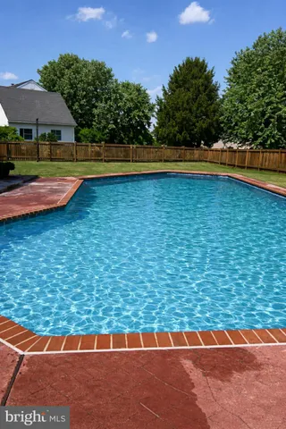 a view of swimming pool with lawn chairs under an umbrella