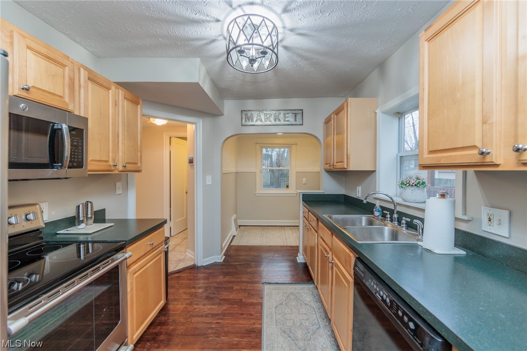 2199 Cranston Road Cleveland, OH 44118 - Photo 8 of 40 Kitchen with dark hardwood / wood-style flooring, an inviting chandelier, appliances with stainless steel finishes, a textured ceiling, and sink