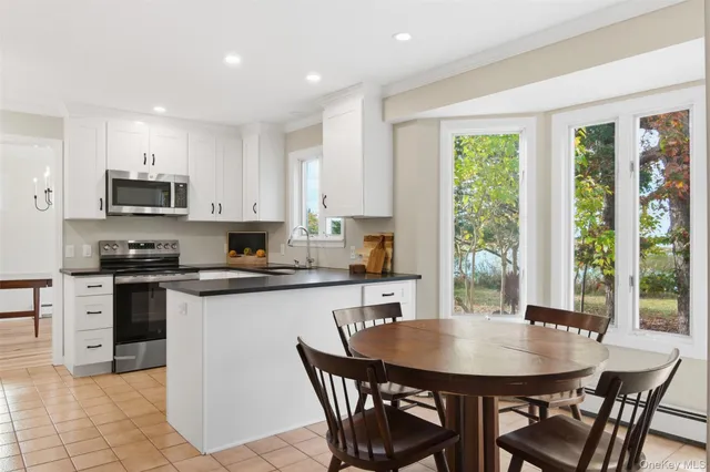 a kitchen with stainless steel appliances granite countertop a stove a sink a microwave a dining table and chairs