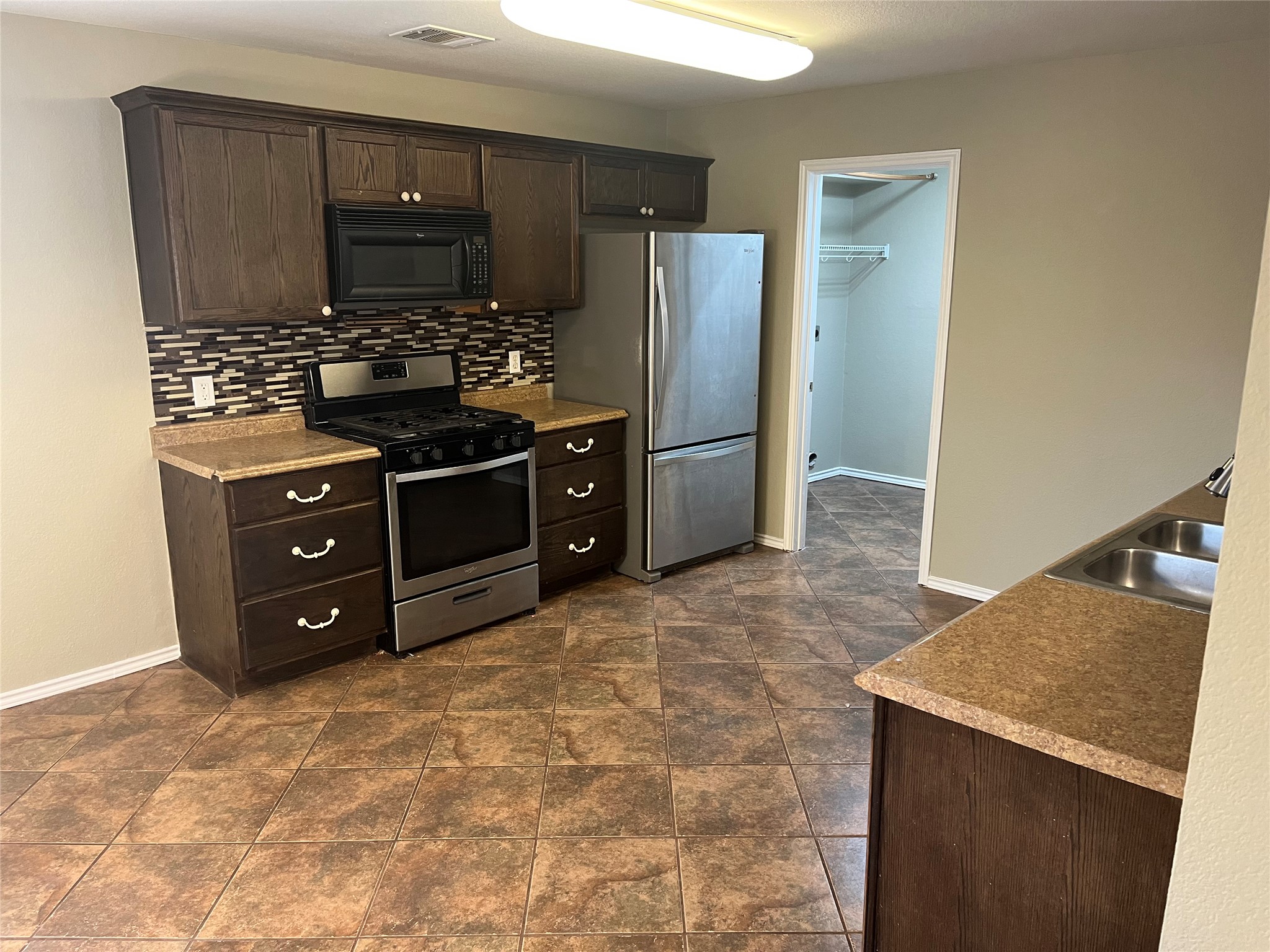 694 Hogan Kyle, TX 78640 - Photo 6 of 20 Kitchen featuring dark wood finish cabinets, stainless steel appliances, light countertops, and decorative backsplash