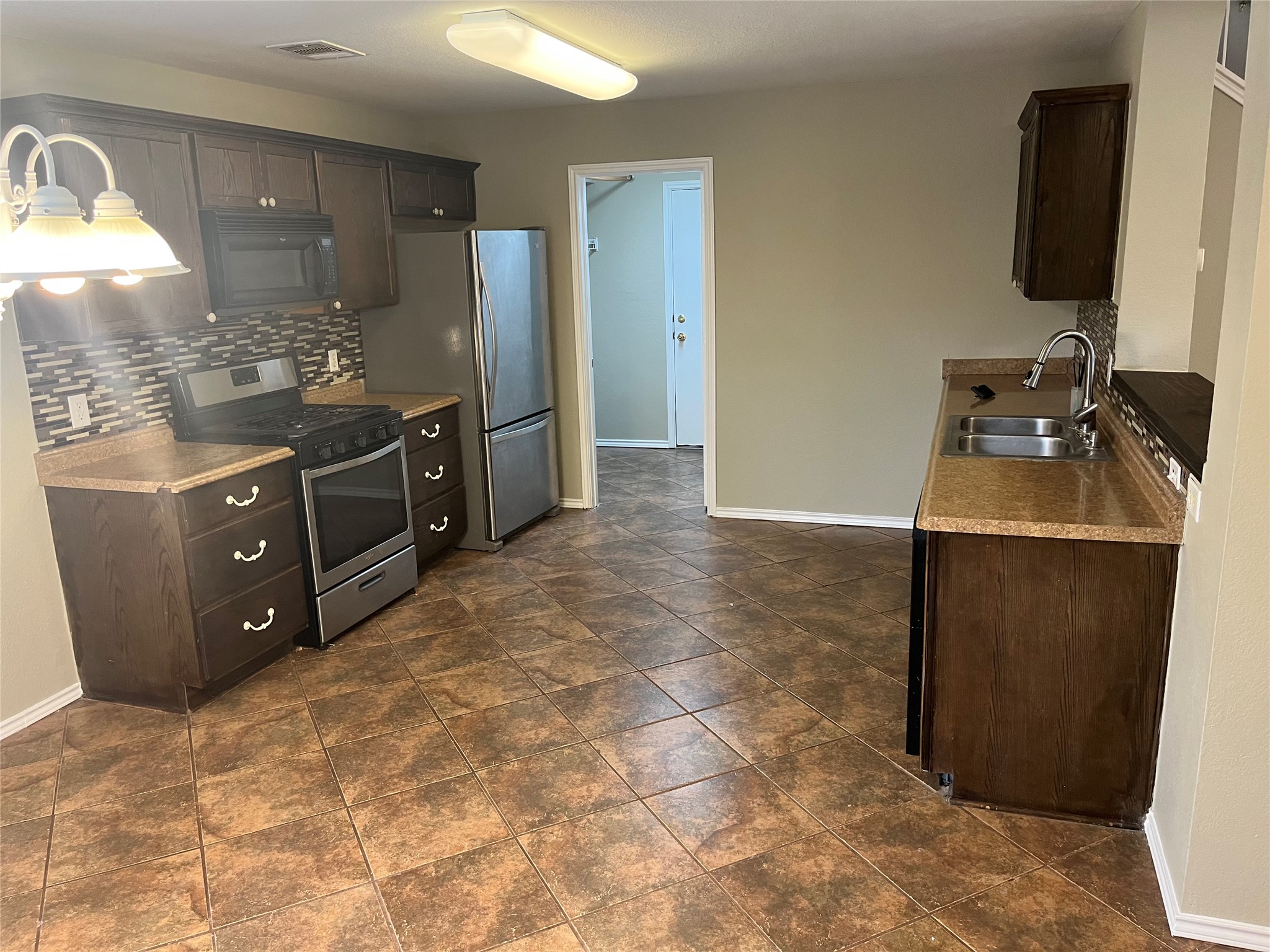 694 Hogan Kyle, TX 78640 - Photo 7 of 20 Kitchen featuring dark wood finish cabinetry, stainless steel appliances, and tasteful backsplash