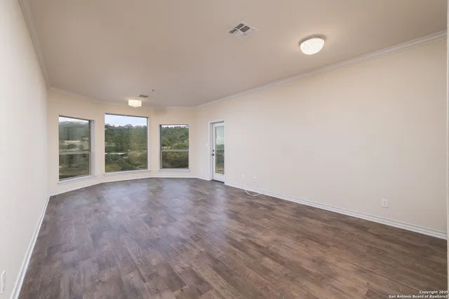 a view of an empty room with a window and wooden floor
