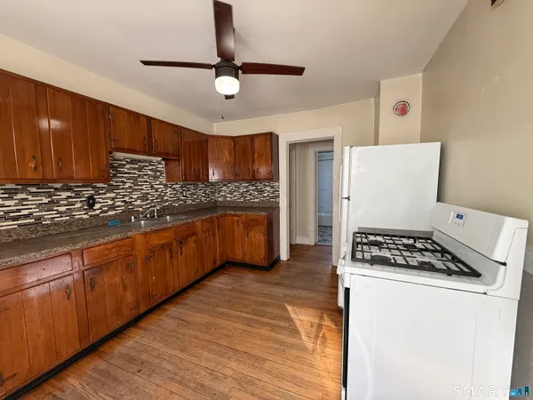 a kitchen with granite countertop a stove cabinets and wooden floor