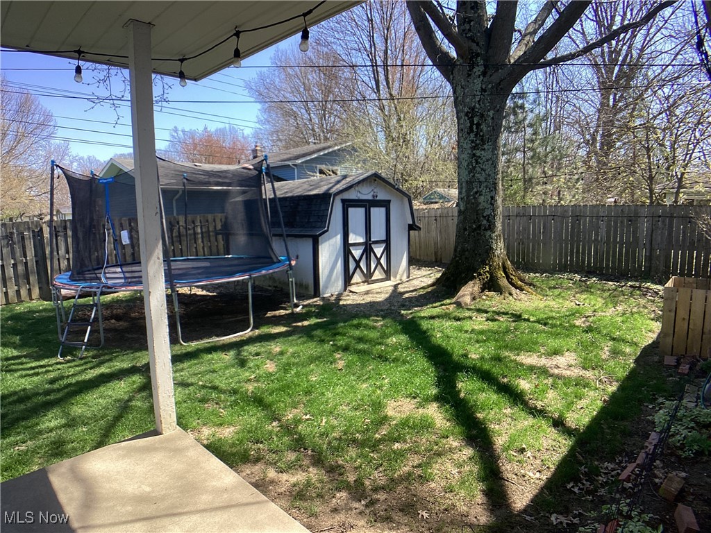 9083 Priem Road Strongsville, OH 44149 - Photo 26 of 28 View of yard with a fenced backyard, a shed, an outdoor structure, and a trampoline