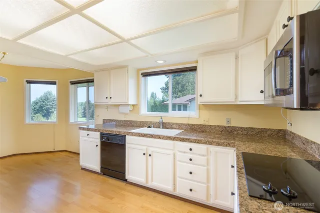 a kitchen with granite countertop a sink cabinets stainless steel appliances and a window