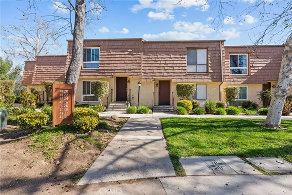 a front view of a house with a yard and potted plants