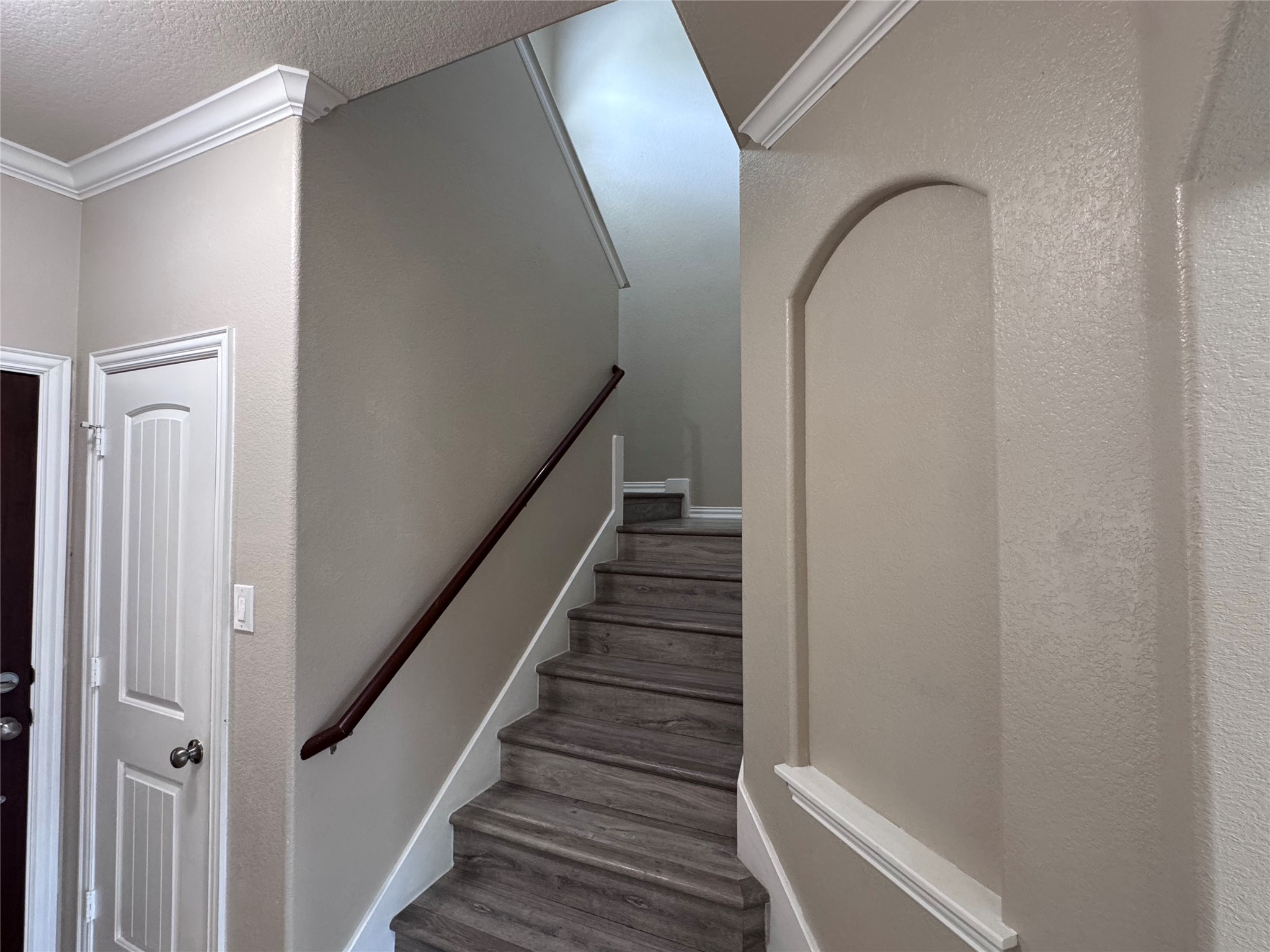 2605 Rough Berry Road Pflugerville, TX 78660 - Photo 17 of 40 Elegant crown molding and an arched alcove frame a graceful staircase with rich wood-toned treads.