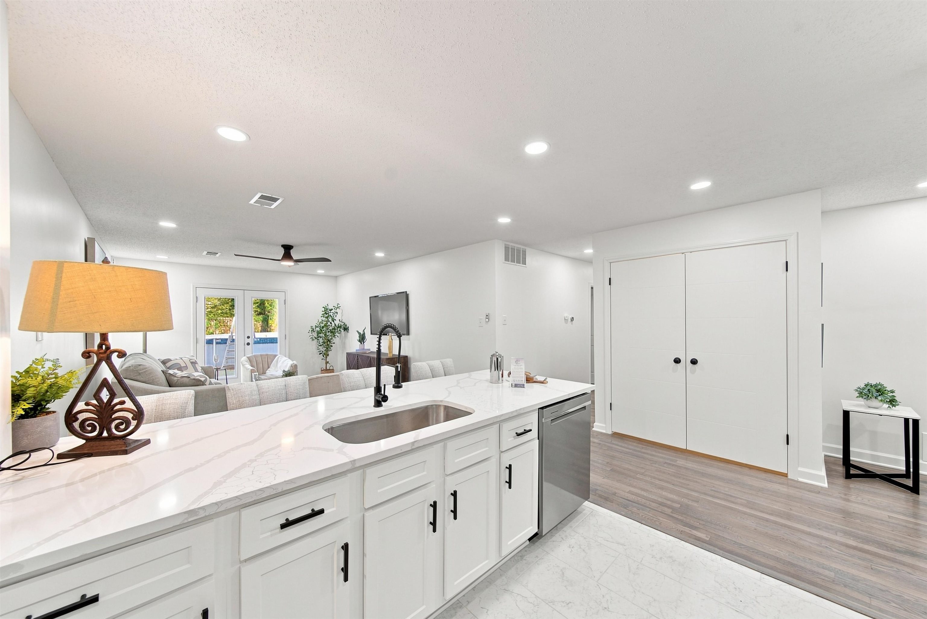 458 Gerald Road Memphis, TN 38122 - Photo 17 of 37 Kitchen island with stone-finish countertops, stainless steel sink with a matte black faucet, and white cabinetry with matte black hardware
