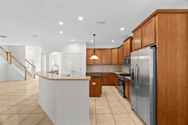 a kitchen with stainless steel appliances granite countertop a refrigerator a sink a stove and oven