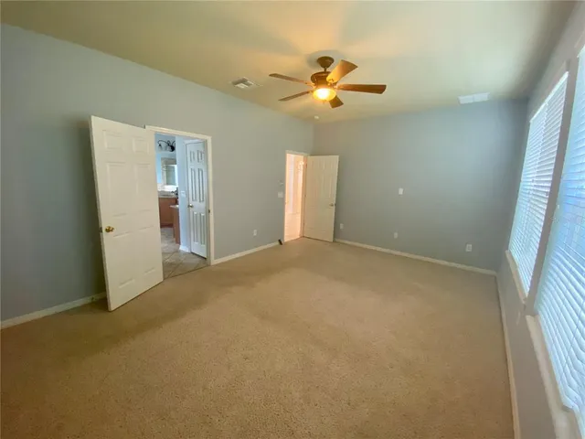 an empty room with a chandelier fan and windows