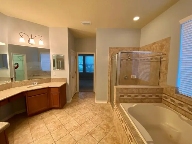 a spacious bathroom with a tub sink shower and mirror