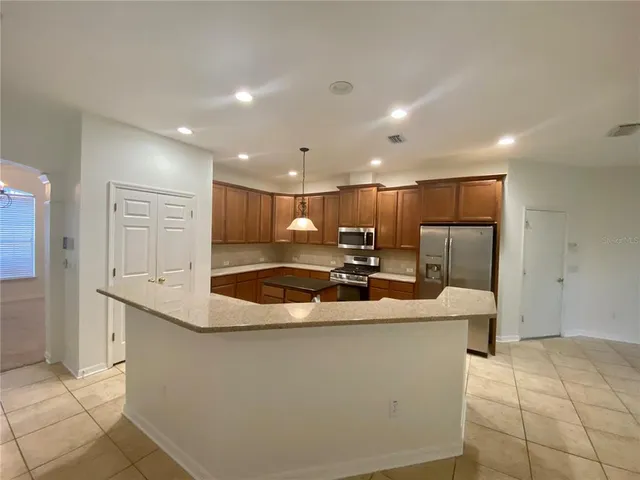 a large kitchen with stainless steel appliances kitchen island a stove a refrigerator a sink and a cabinets
