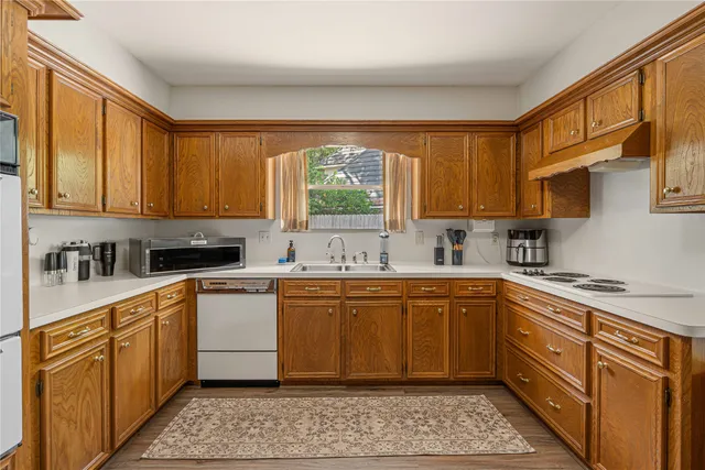 a kitchen with stainless steel appliances granite countertop a sink a stove cabinets and a window