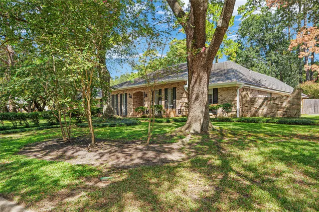 a view of house in front of a big yard with large trees