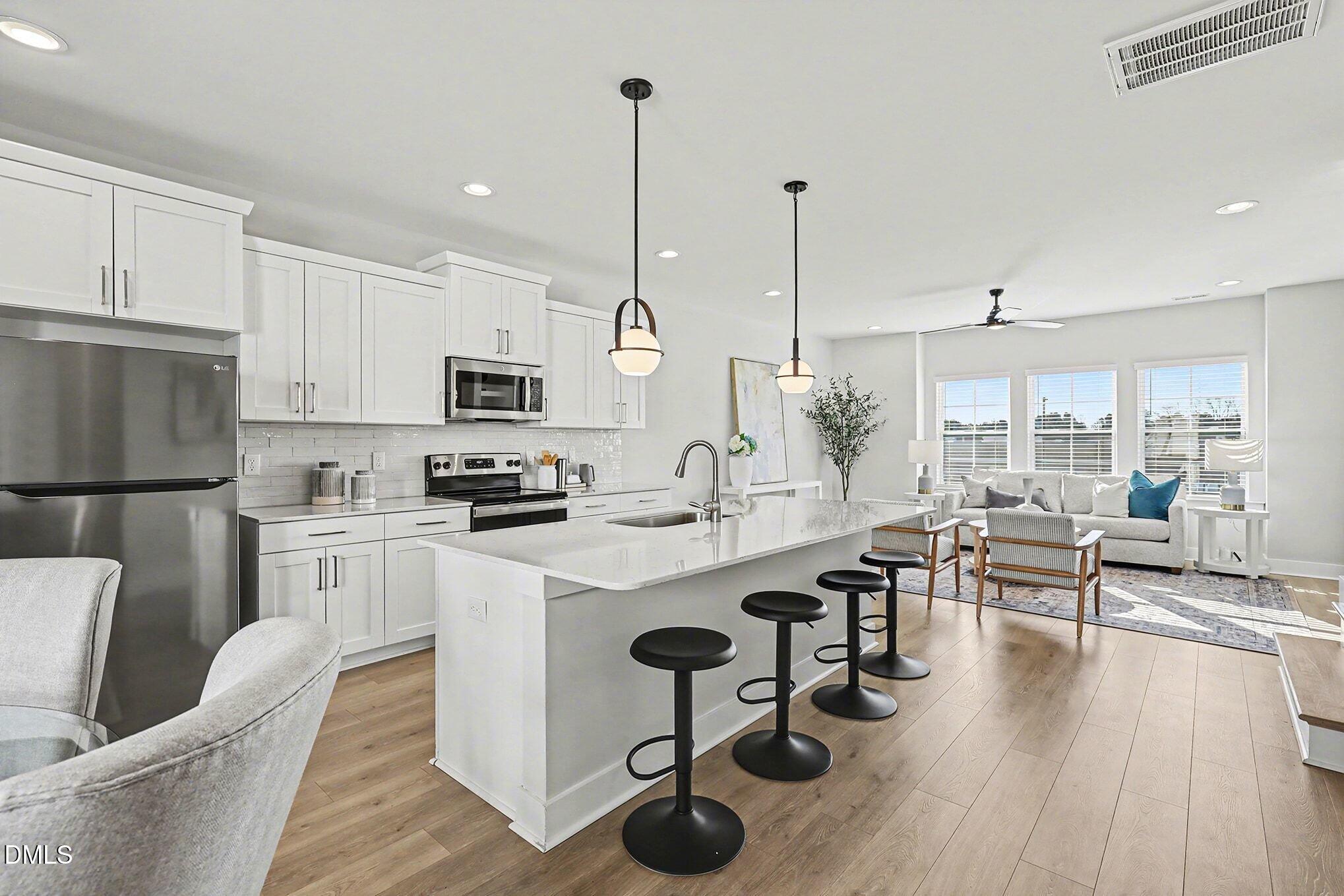 8512 Silsbee Drive Raleigh, NC 27613 - Photo 13 of 42 a kitchen with stainless steel appliances granite countertop a refrigerator a stove oven a sink dishwasher and white cabinets with wooden floor