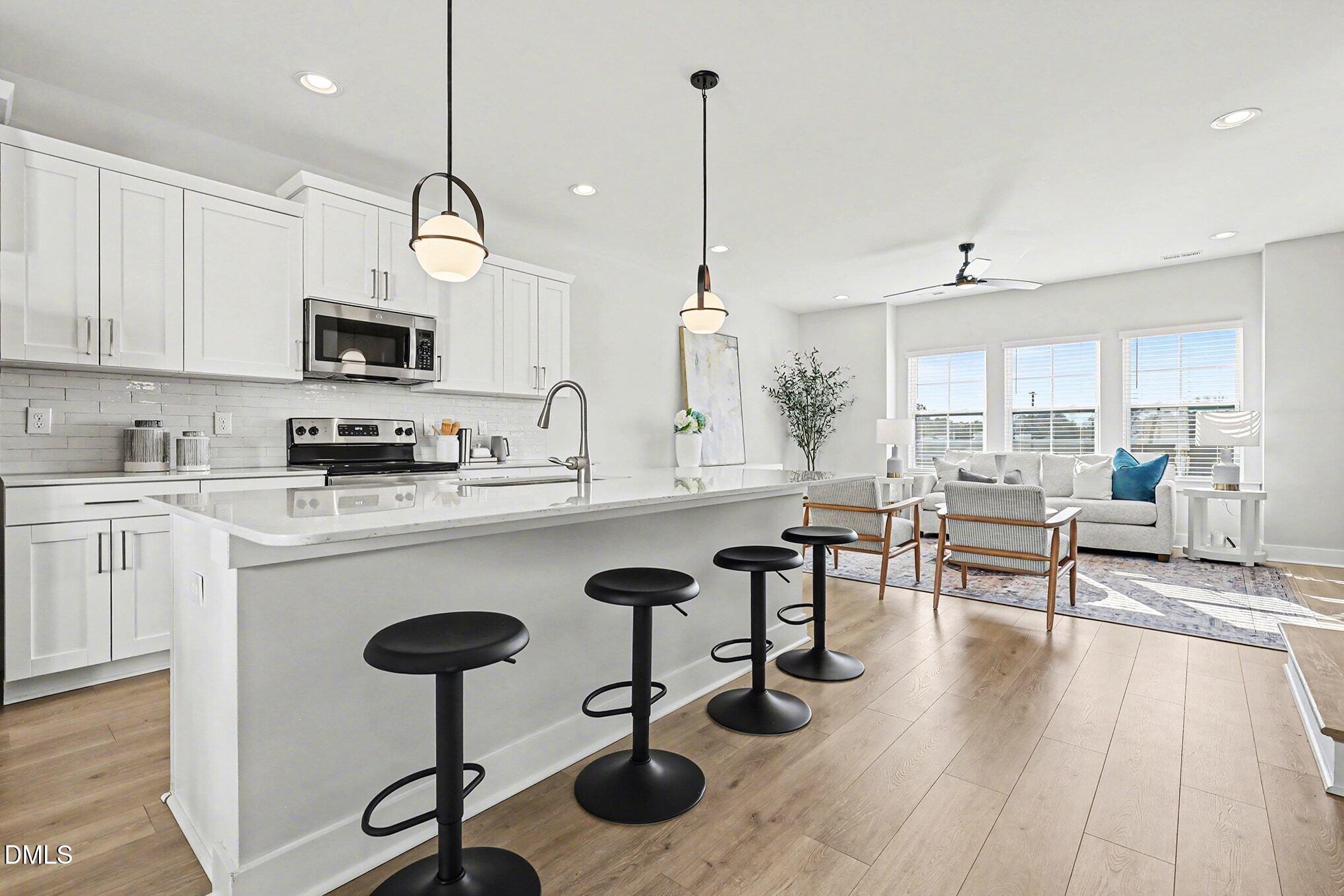 8512 Silsbee Drive Raleigh, NC 27613 - Photo 14 of 42 a kitchen with stainless steel appliances granite countertop a stove a sink a refrigerator and chairs with wooden floor