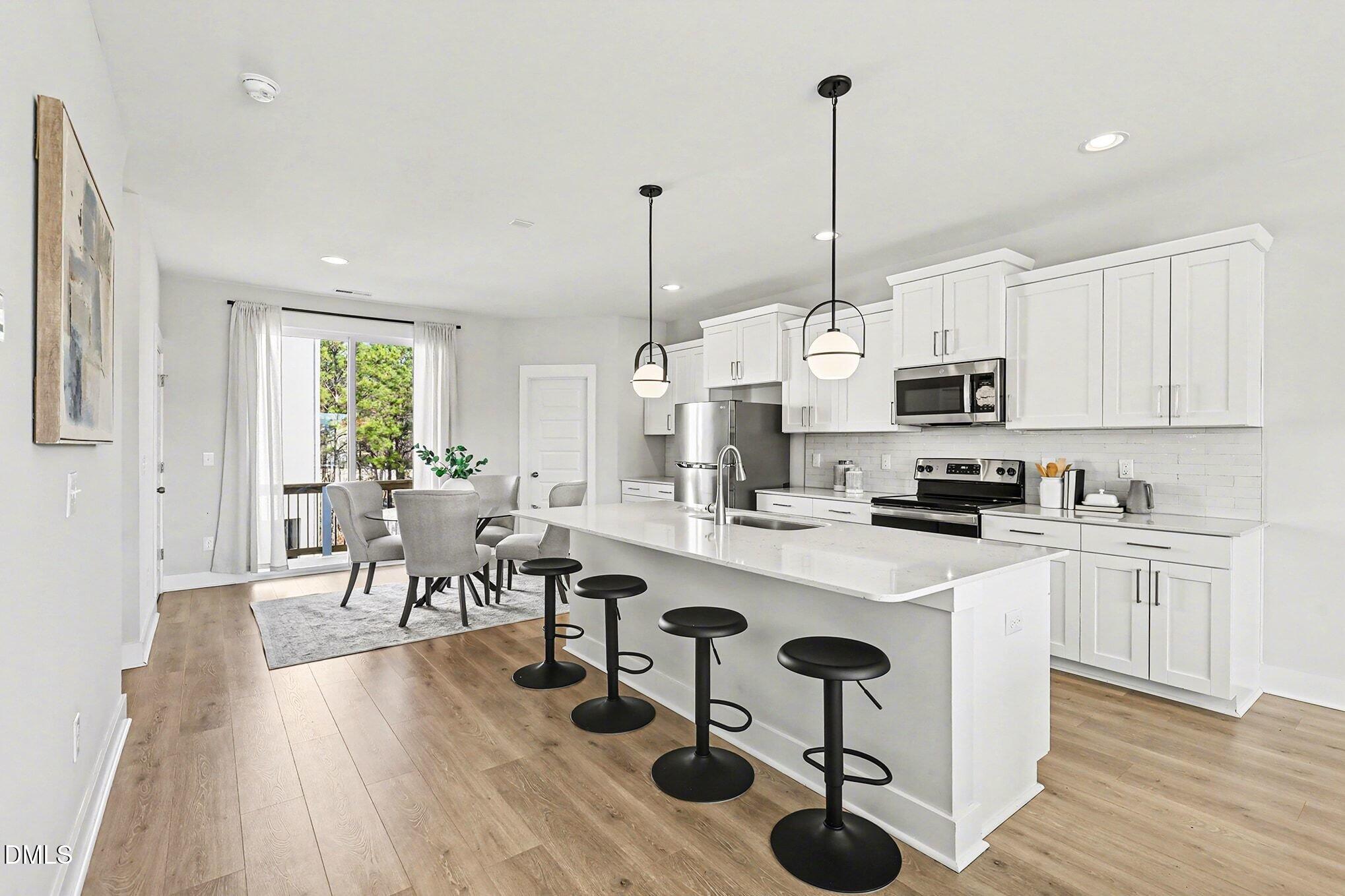 8512 Silsbee Drive Raleigh, NC 27613 - Photo 23 of 42 a kitchen with stainless steel appliances kitchen island wooden floors and white cabinets
