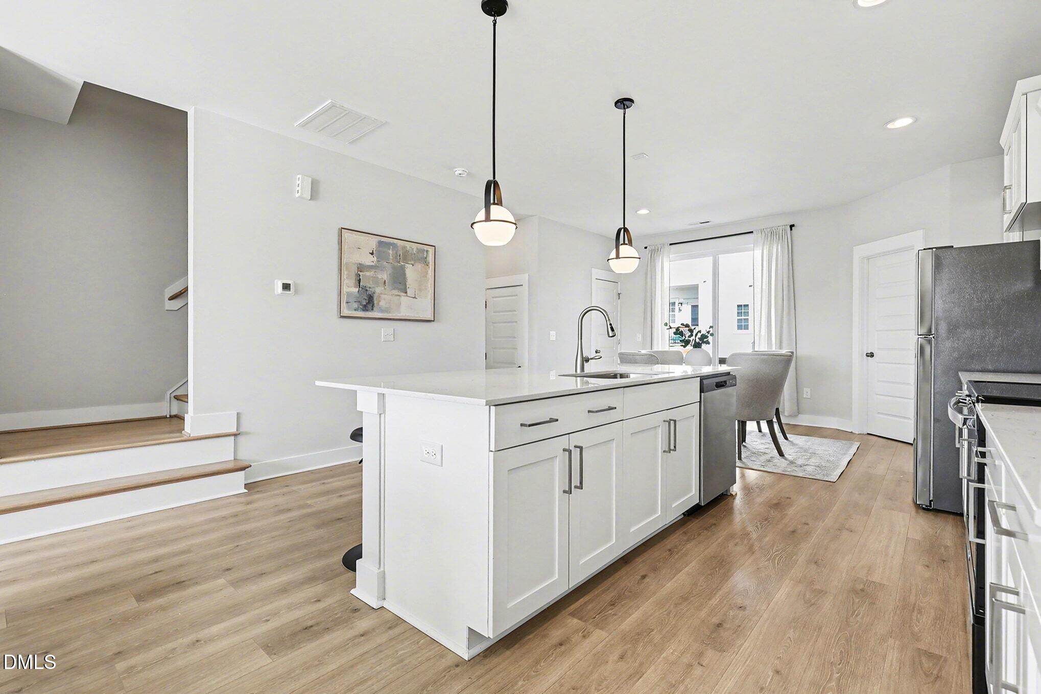 8512 Silsbee Drive Raleigh, NC 27613 - Photo 24 of 42 a kitchen with stainless steel appliances granite countertop a refrigerator a sink dishwasher a oven with white cabinets and wooden floor