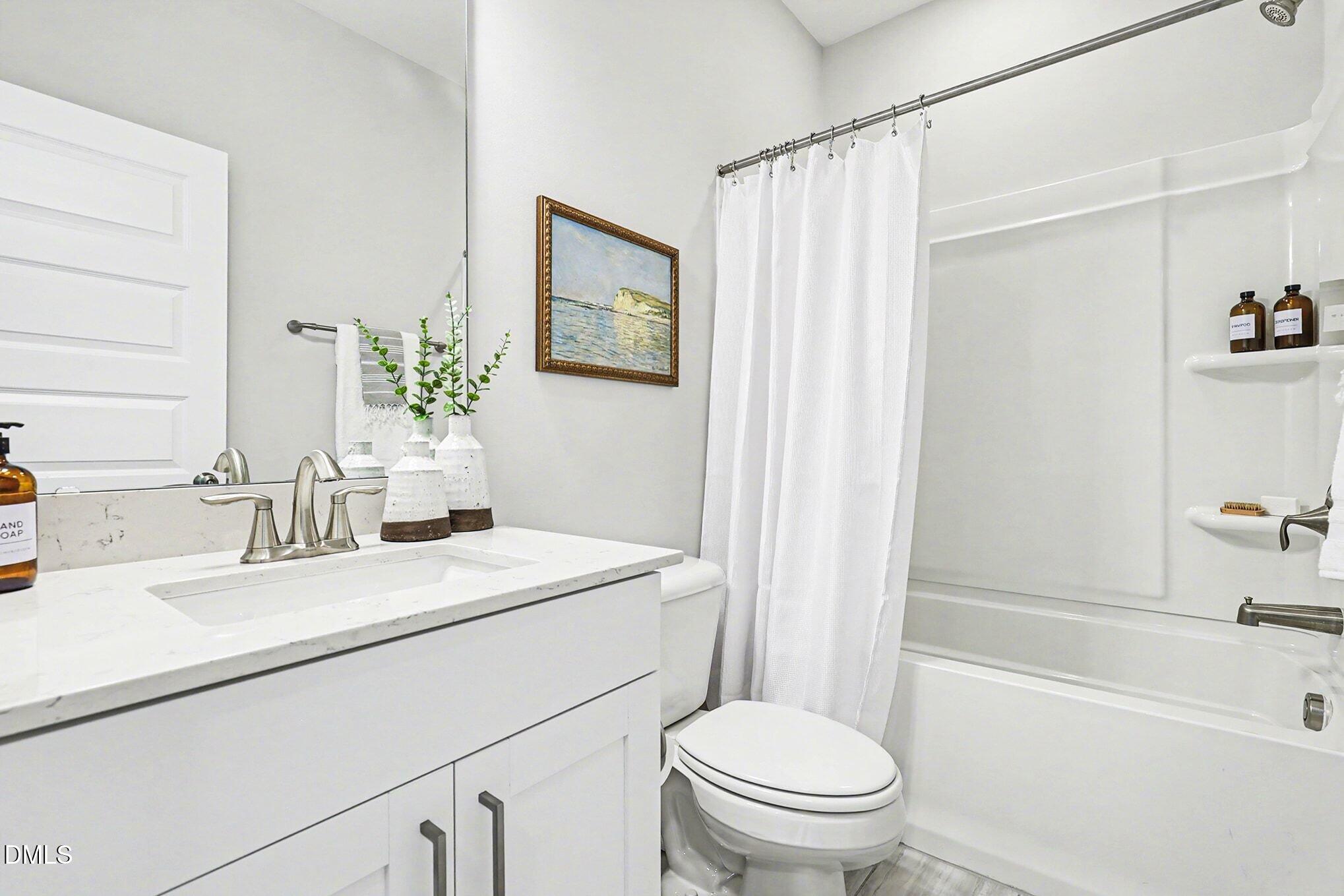 8512 Silsbee Drive Raleigh, NC 27613 - Photo 30 of 42 a bathroom with a sink a toilet a mirror a vanity and shower