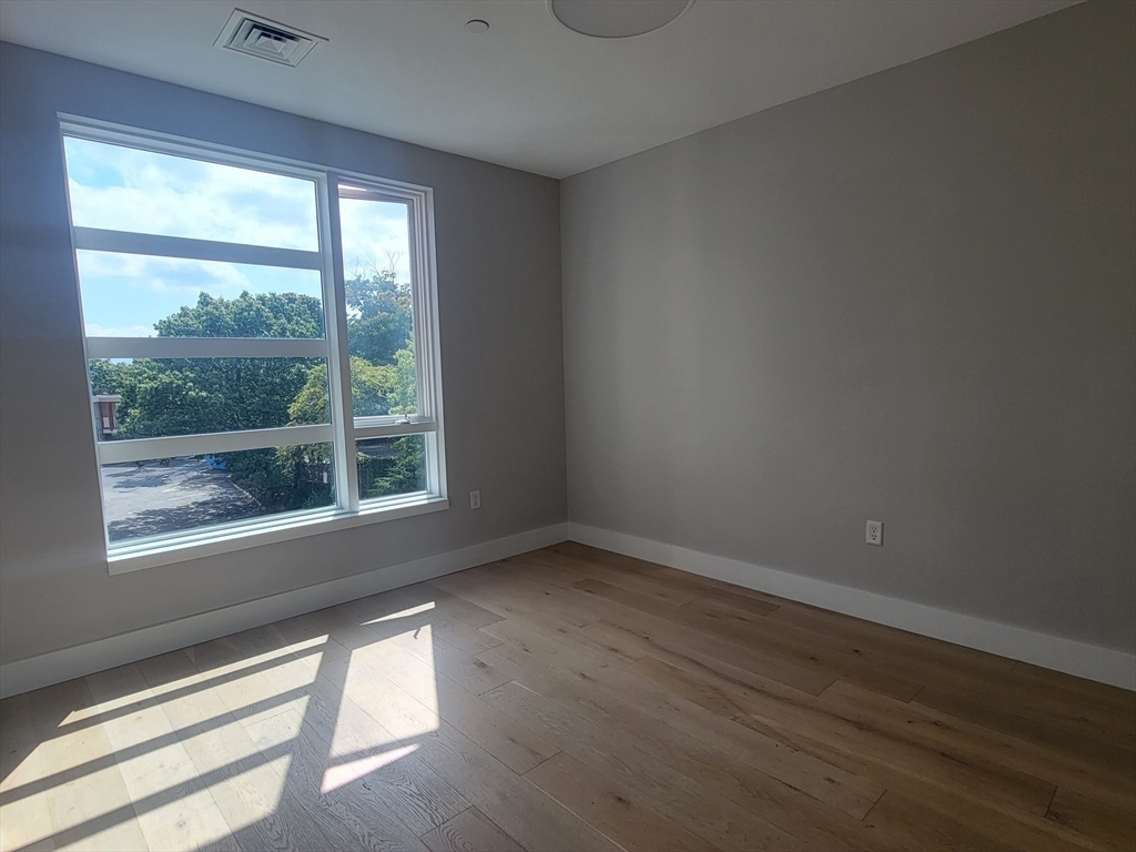 1650 Commonwealth Avenue, Unit 304A Boston, MA 02135 - Photo 17 of 26 a view of an empty room with wooden floor and a window