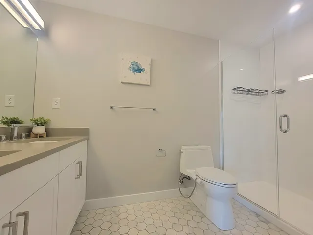 a bathroom with a granite countertop sink a toilet and shower