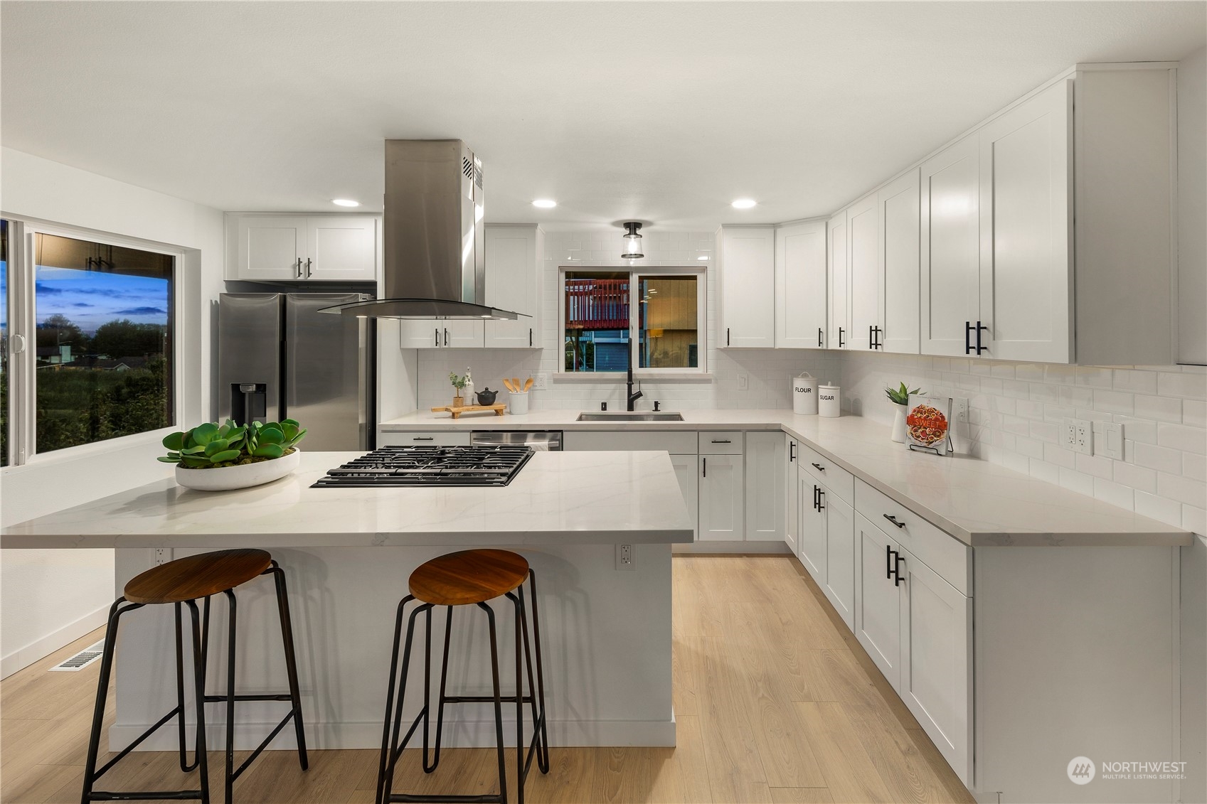 2823 South Bateman Street Seattle, WA 98108 - Photo 11 of 39 a kitchen with stainless steel appliances a stove a sink a refrigerator and white cabinets with wooden floor