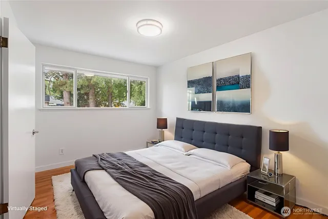 a bedroom with a bed and a large mirror next to a window