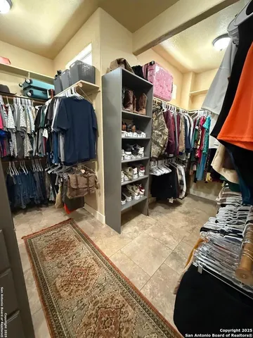 a view of walk in closet with clothes and shoes