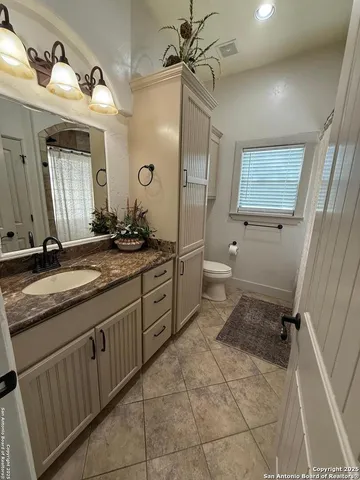 a bathroom with a granite countertop sink a toilet and shower