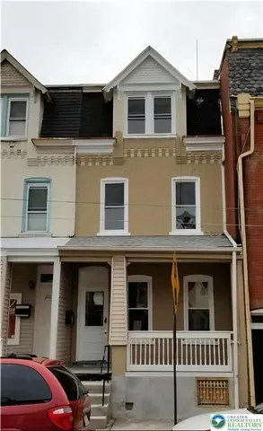 a view of a house with a cars park side of a road