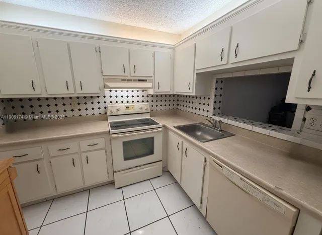 a kitchen with white cabinets and appliances
