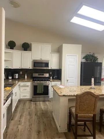 a kitchen with stainless steel appliances kitchen island granite countertop a stove a sink and a refrigerator