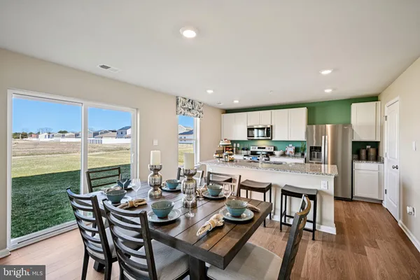 a room with stainless steel appliances kitchen island granite countertop a dining table and chairs