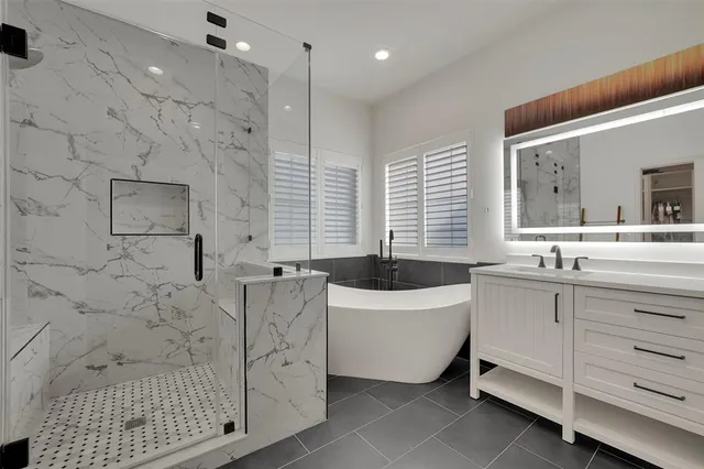 a bathroom with a sink a bathtub a mirror a vanity and a shower