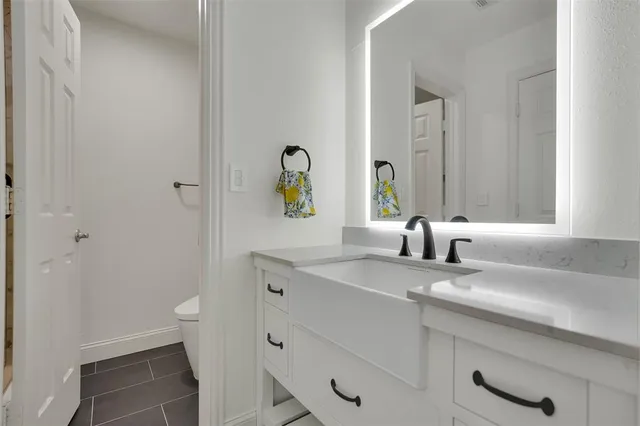 a bathroom with a granite countertop sink and a toilet