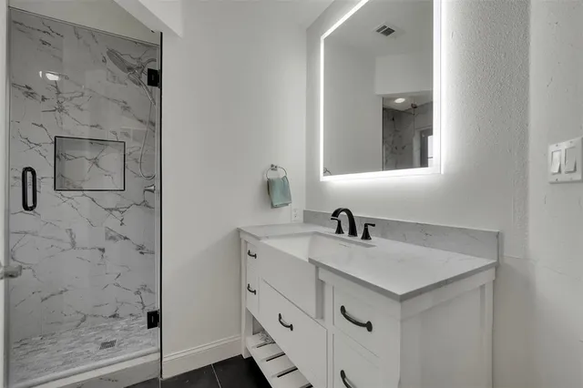 a bathroom with a sink vanity and shower