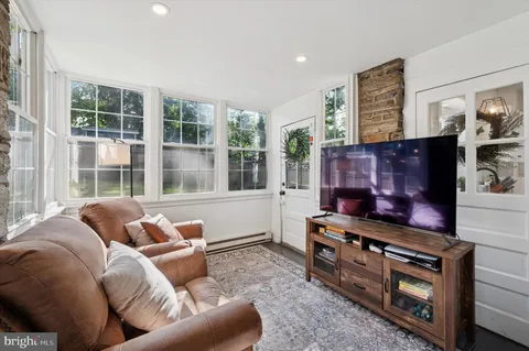 a living room with furniture a flat screen tv and floor to ceiling windows