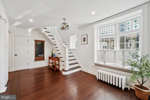 a view of an empty room with wooden floor and stairs