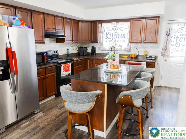 a kitchen with stainless steel appliances granite countertop a refrigerator a sink a stove and white cabinets