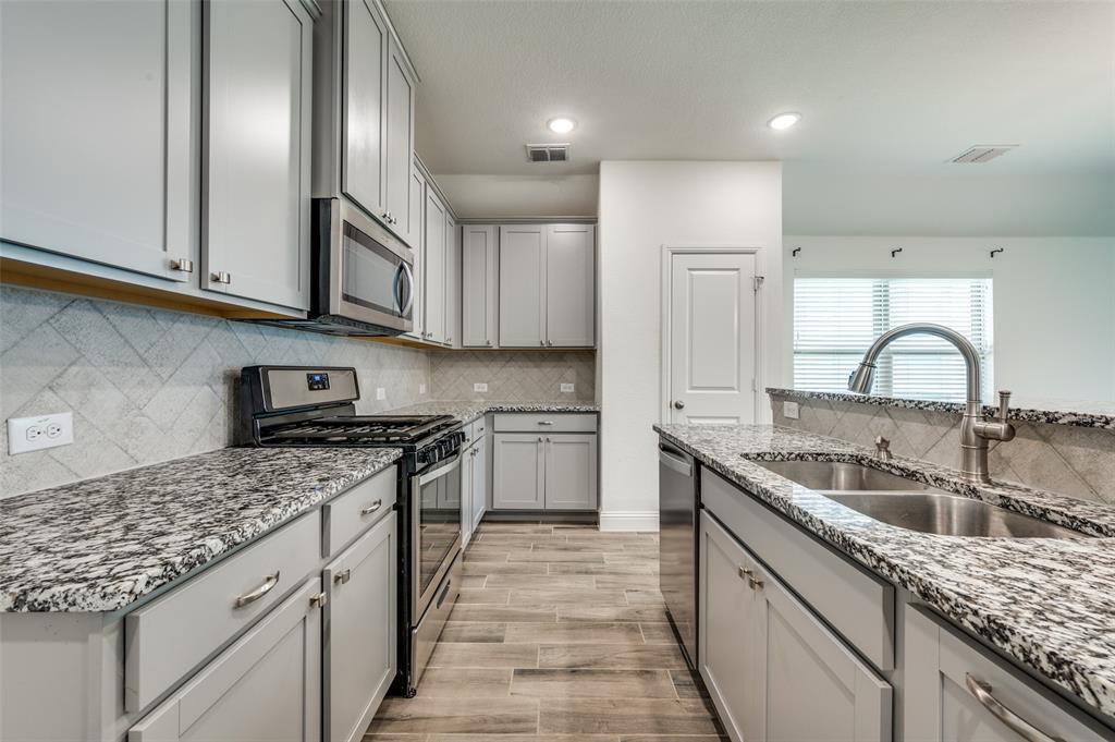 7025 Trailhead Street Little Elm, TX 76227 - Photo 12 of 25 a kitchen with stainless steel appliances granite countertop a sink stove and cabinets