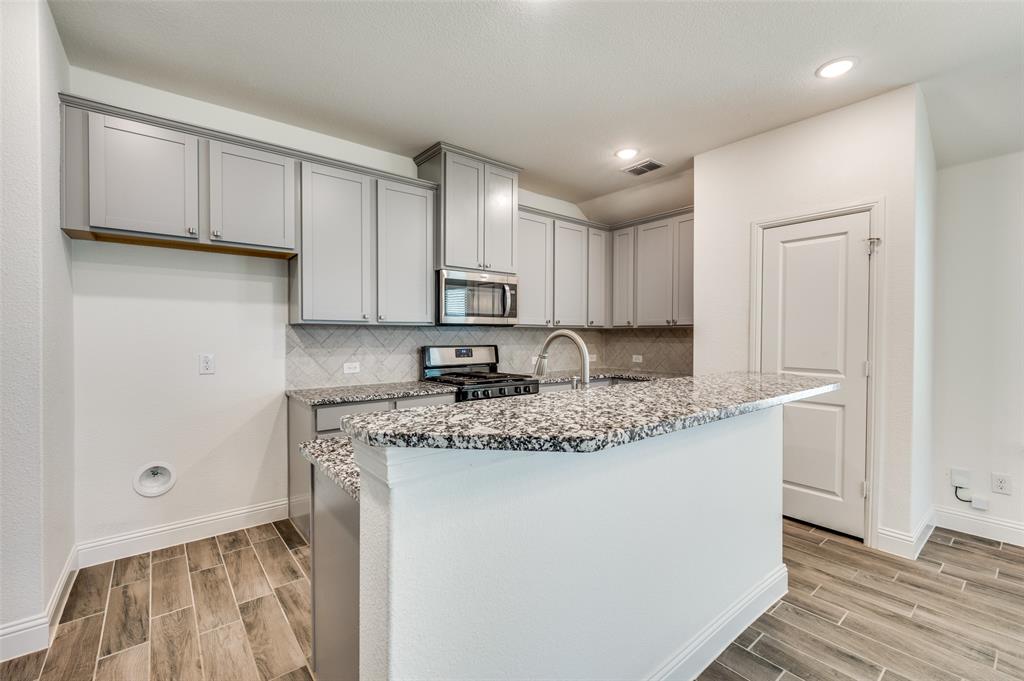 7025 Trailhead Street Little Elm, TX 76227 - Photo 13 of 25 a kitchen with stainless steel appliances granite countertop a sink stove and cabinets