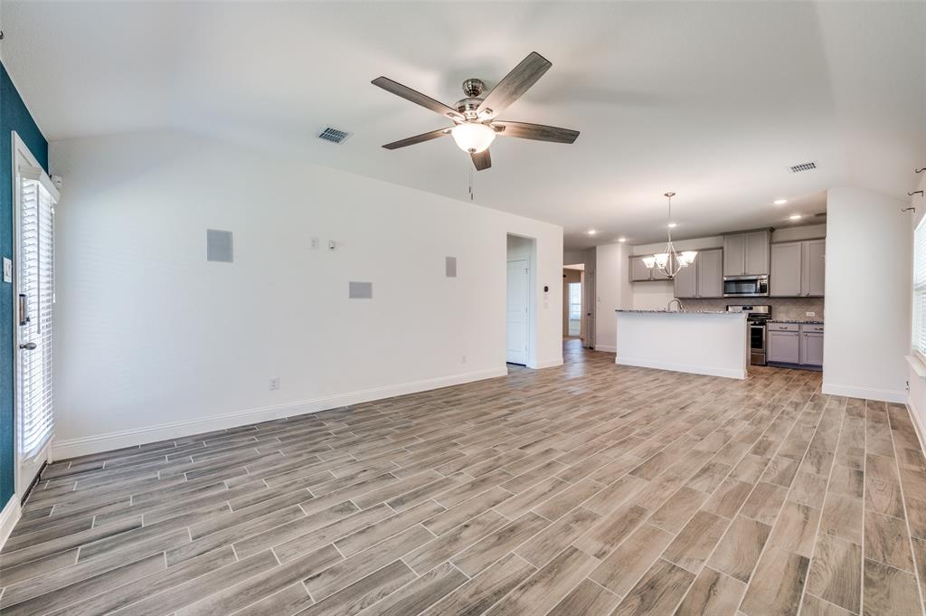 7025 Trailhead Street Little Elm, TX 76227 - Photo 6 of 25 a view of a livingroom with a kitchen space with wooden floor and a ceiling fan