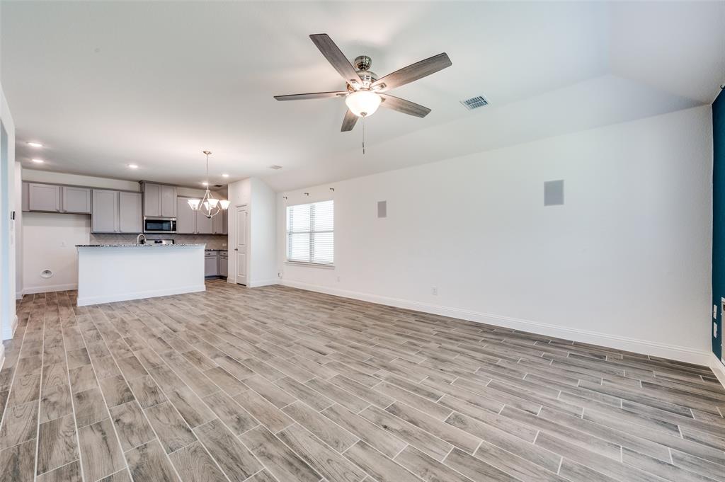 7025 Trailhead Street Little Elm, TX 76227 - Photo 7 of 25 a view of a kitchen with a sink dishwasher a refrigerator with wooden floor and cabinets