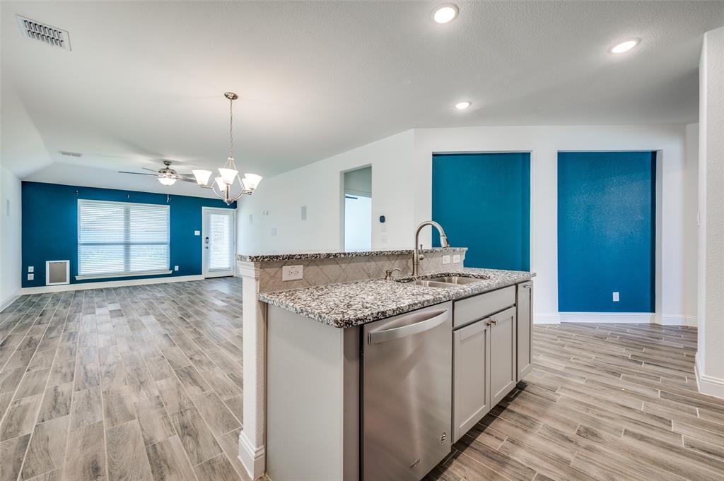 7025 Trailhead Street Little Elm, TX 76227 - Photo 9 of 25 a kitchen with kitchen island granite countertop a sink and a stove